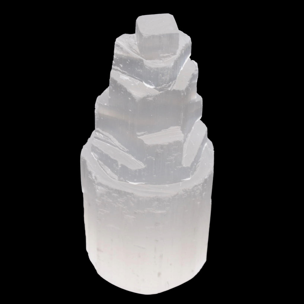 A natural selenite crystal tower with a stepped, fractal structure, shown against a solid black background.