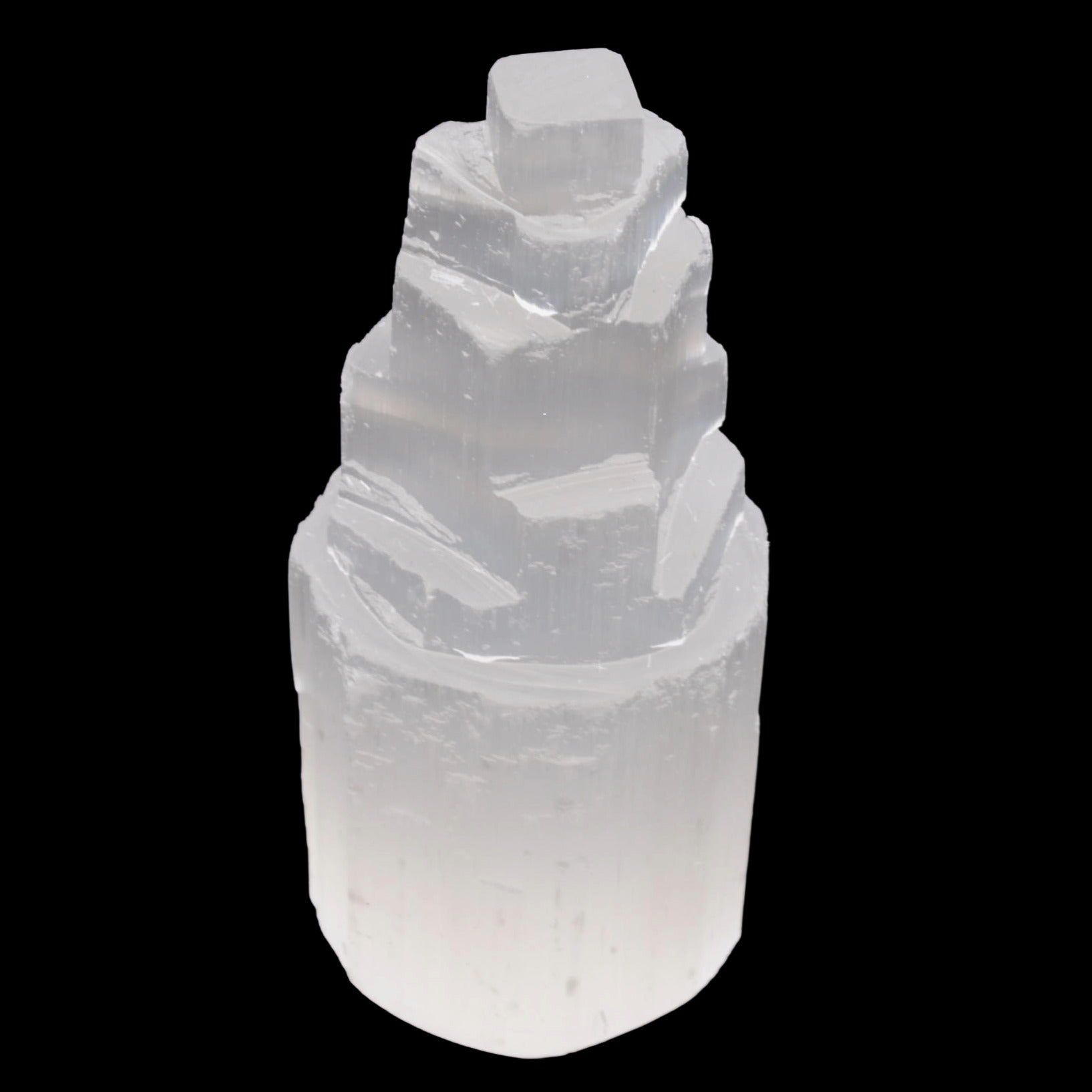A natural selenite crystal tower with a stepped, fractal structure, shown against a solid black background.