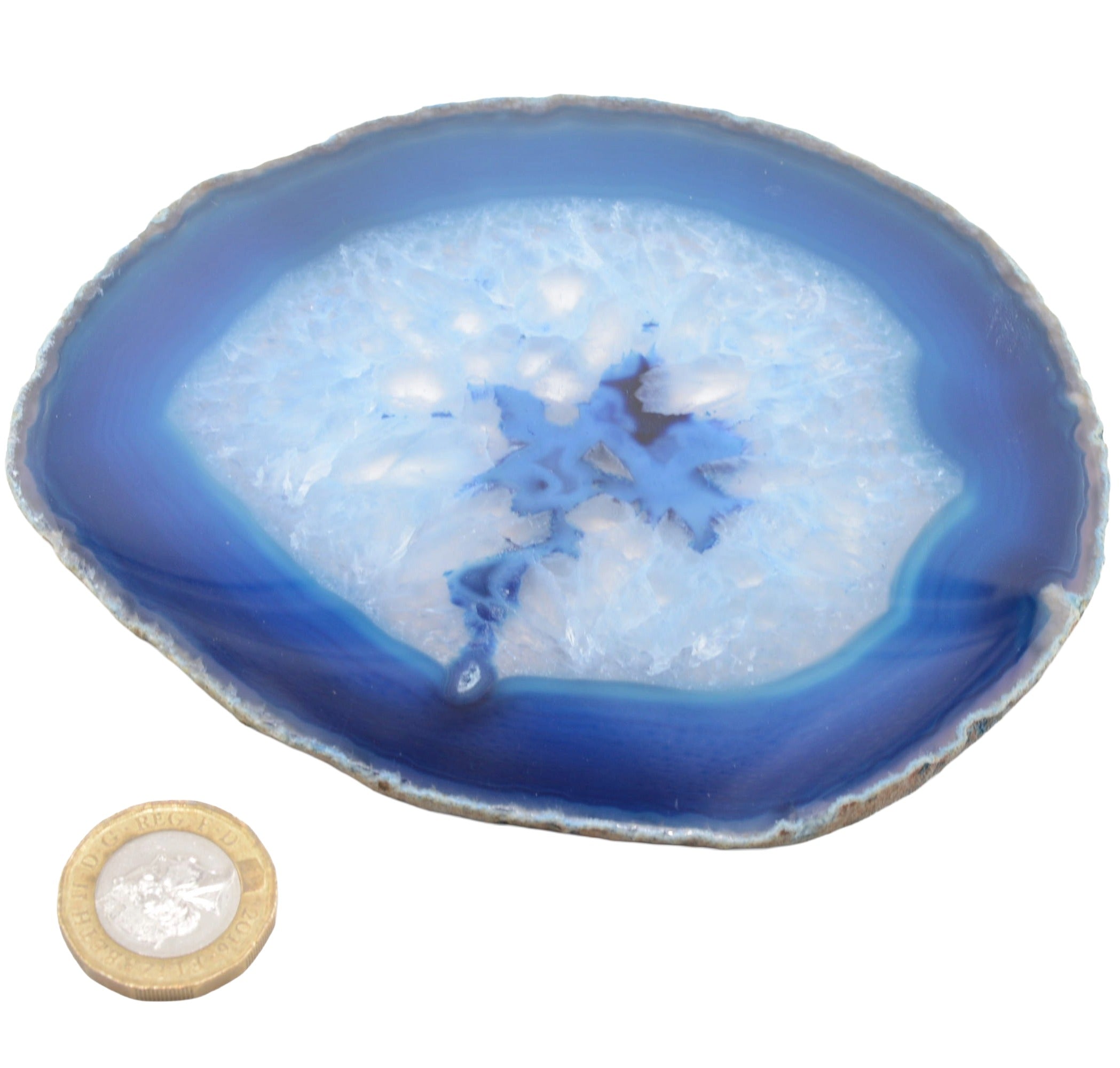 A polished agate slice with concentric bands of deep blue, medium blue, and a frosted pale blue center, shown on a white background with a coin for scale.