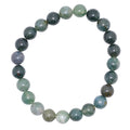 A beaded stretch bracelet made of polished moss agate gemstone beads in shades of green, white and clear. arranged in a circle on a plain white background.