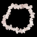 A circular bracelet made of small, irregular pink rose quartz crystal chips, photographed on a dark textured gray background.