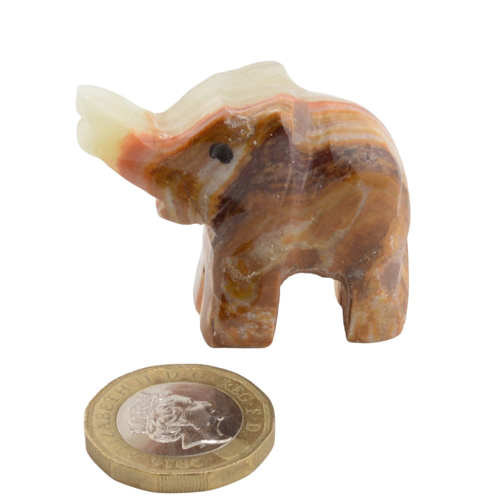 A small carved elephant figurine made from banded calcite in brown, tan, cream, and orange tones, shown next to a coin for scale on a plain white background.