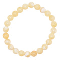 A beaded stretch bracelet made of smooth, round yellow calcite, arranged in a circular shape against a plain white background.